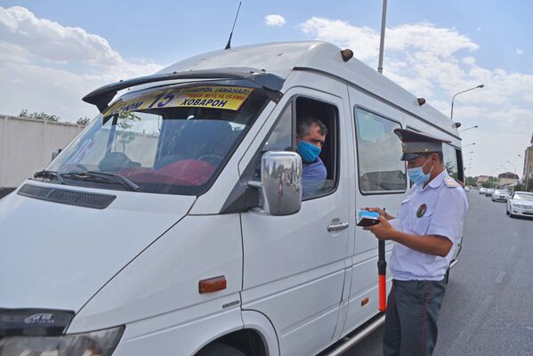 Сотрудник милиции проверяет документы у водителя маршрутки в Душанбе - Sputnik Таджикистан
