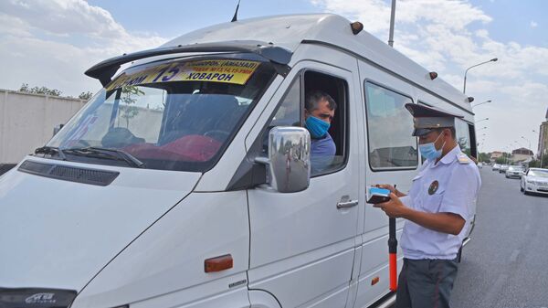 Сотрудник милиции проверяет документы у водителя маршрутки в Душанбе - Sputnik Таджикистан