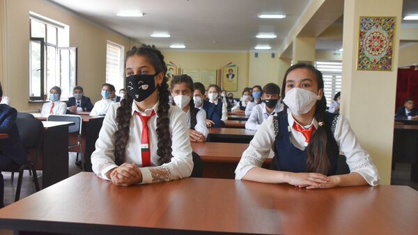 Школьники сидят за партой в защитных масках - Sputnik Таджикистан