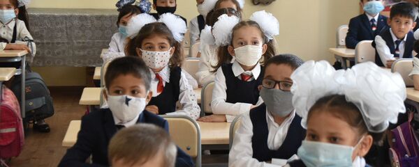 Школьники сидят за партой в защитных масках - Sputnik Тоҷикистон