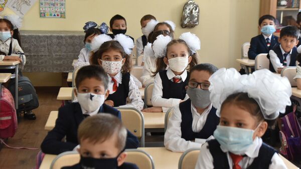Школьники сидят за партой в защитных масках - Sputnik Таджикистан