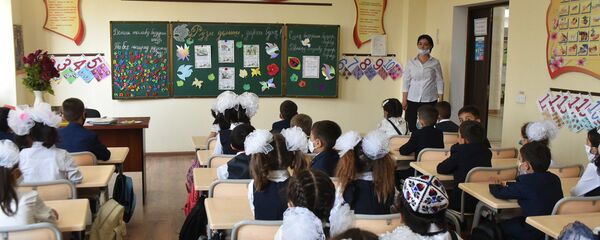 Школьники сидят за партой в защитных масках - Sputnik Тоҷикистон