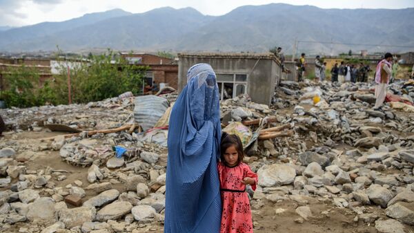  Женщина с ребенком у разрушенного здания после наводнения в Афганистане - Sputnik Тоҷикистон