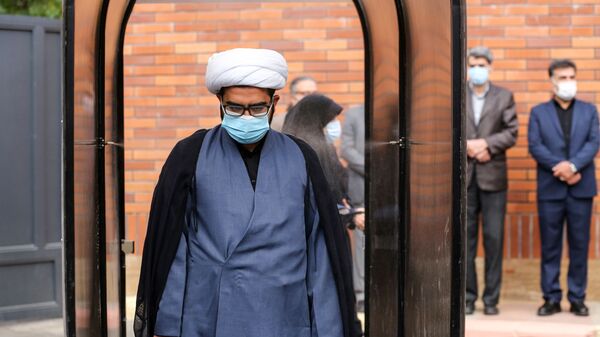 Иранский чиновник в маске во время прохождения дезинфекции в школе в Тегеране  - Sputnik Тоҷикистон