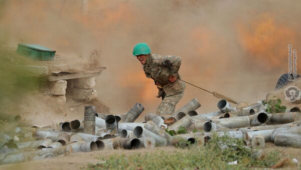 Военнослужащий стреляет из артиллерийского орудия во время боя с азербайджанскими силами в Нагорном Карабахе - Sputnik Таджикистан