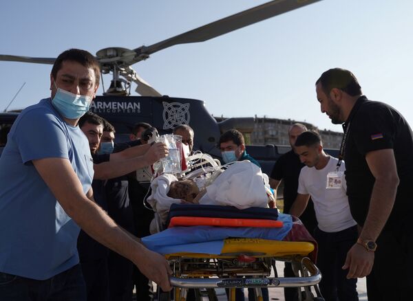 А на этом фото раненых с линии фронта доставляют в больницы. На фото - раненого на носилках транспортируют в медицинский центр Эребуни в Ереване - Sputnik Таджикистан