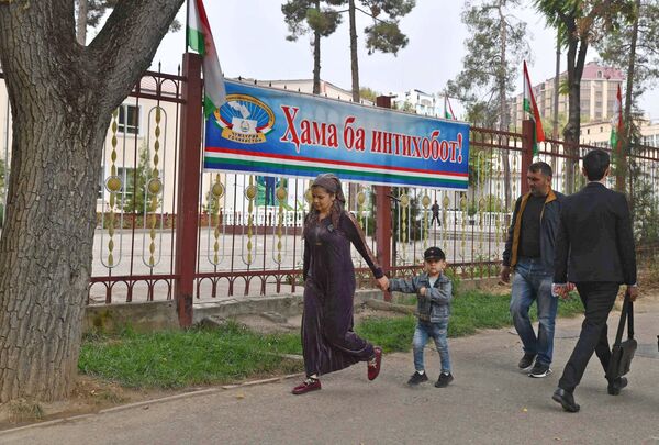 Люди идут по улице Душанбе мимо плаката Все на выборы! - Sputnik Таджикистан