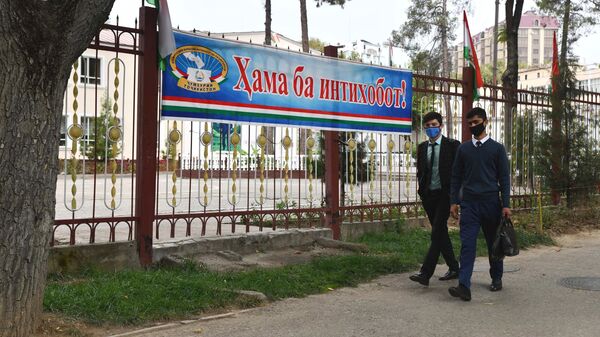Люди идут по улице Душанбе мимо плаката Все на выборы! - Sputnik Таджикистан