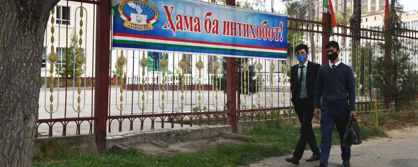 Люди идут по улице Душанбе мимо плаката Все на выборы! - Sputnik Таджикистан