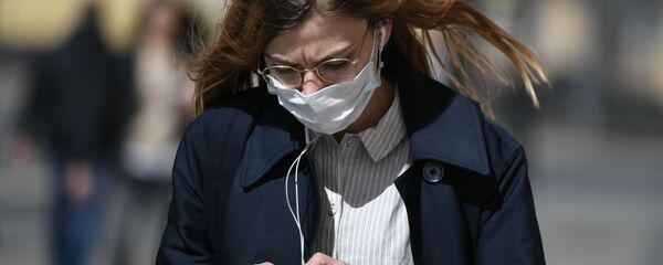 Девушка в защитной маске идет по улице - Sputnik Тоҷикистон