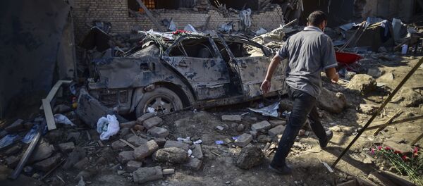 Мужчина идет среди обломков поврежденных домов в Гяндже, Азербайджан - Sputnik Тоҷикистон