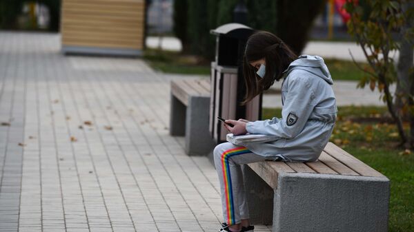 Девочка сидит на лавочке с телефоном - Sputnik Таджикистан
