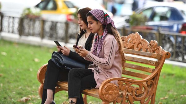 Девушки сидят на скамейке в парке - Sputnik Таджикистан