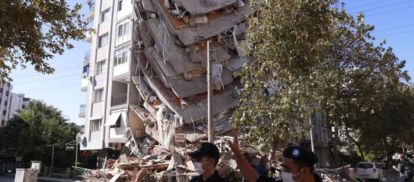 Полиция напротив разрушенного здания в результате землетрясения в Измире  - Sputnik Тоҷикистон