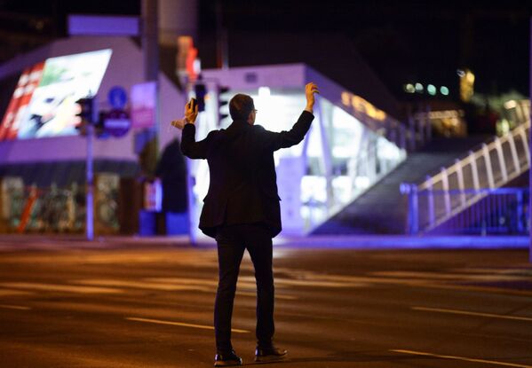 Мужчина поднимает руки, пока полицейские проверяют его на улице после перестрелки в Вене - Sputnik Таджикистан