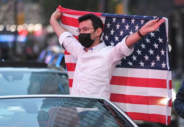 Человек с флагом США на Таймс-сквер в Нью-Йорке после новостей о победе на выборах президента США кандидата от Демократической партии Джозефа Байдена - Sputnik Тоҷикистон