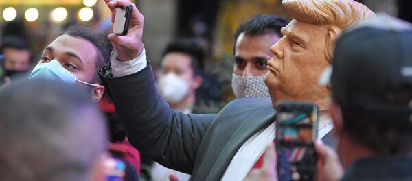 Люди на Таймс-сквер в Нью-Йорке фотографируют человека в маске Дональда Трампа - Sputnik Тоҷикистон