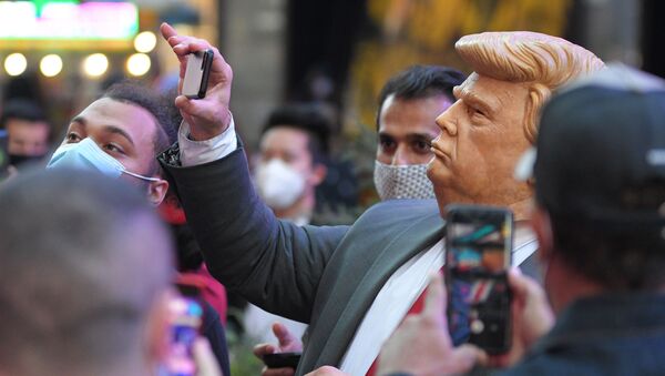 Люди на Таймс-сквер в Нью-Йорке фотографируют человека в маске Дональда Трампа - Sputnik Тоҷикистон