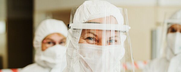 Врач в защитном костюме улыбается - Sputnik Таджикистан