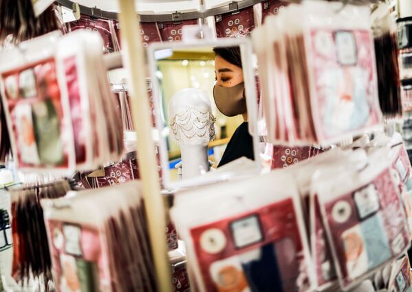 Сотрудник магазина держит маску с драгоценными камнями  в Токио  - Sputnik Тоҷикистон