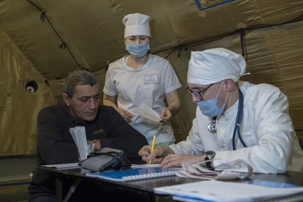 Врач проводит прием пациента на базе госпиталя развернутого Министерством обороны России на территории аэропорта в Степанакерте - Sputnik Тоҷикистон