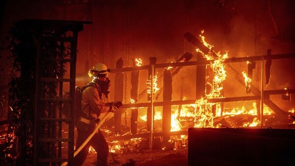 Пожарный борется с пламенем, охватившем постройку, в округе Ориндж, штат Калифорния - Sputnik Таджикистан