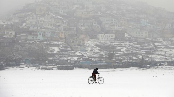 Велосипедист во время снегопада на фоне заснеженного Кабула, Афганистан - Sputnik Таджикистан