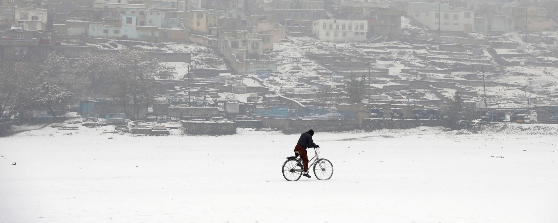Велосипедист во время снегопада на фоне заснеженного Кабула, Афганистан - Sputnik Таджикистан, 1920, 07.10.2021