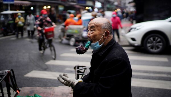 Пожилой мужчина курит трубку на уличном рынке в Ухане - Sputnik Тоҷикистон