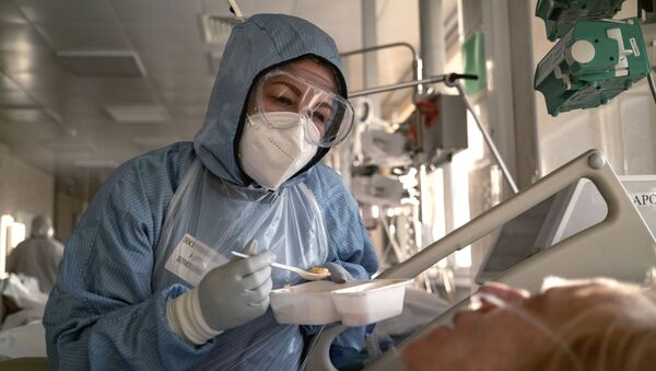 Медицинский сотрудник кормит пациента в отделении реанимации и интенсивной терапии - Sputnik Таджикистан