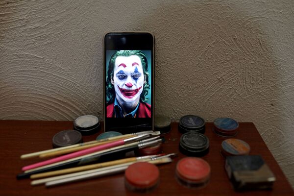 Фото Хоакина Феникса в роли Джокера на экране смартфона иранского артиста Мохаммада - Sputnik Таджикистан