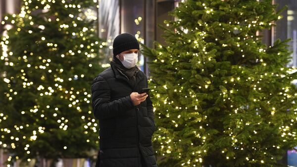 Человек идет по улице вдоль новогодних елок - Sputnik Тоҷикистон