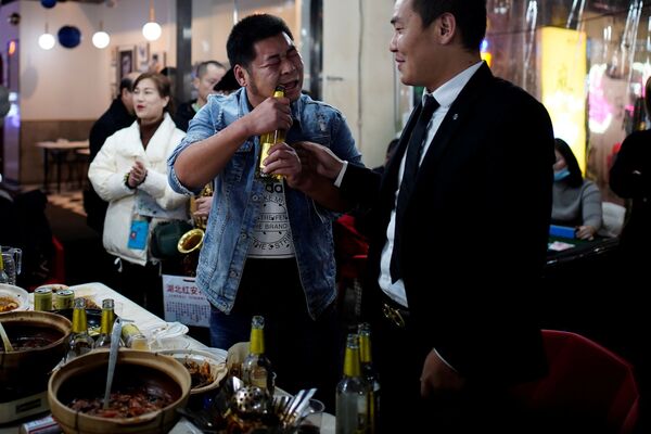 Мужчина открывает пиво зубами в одном из ресторанов Уханя - Sputnik Таджикистан