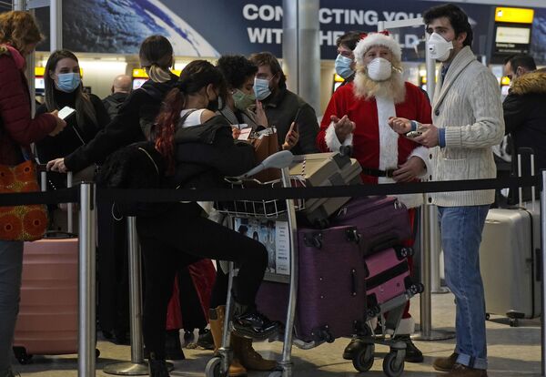 Турист в костюме Санта-Клауса в очереди в зале вылета терминала 2 аэропорта Хитроу в Лондоне, Великобритания - Sputnik Тоҷикистон