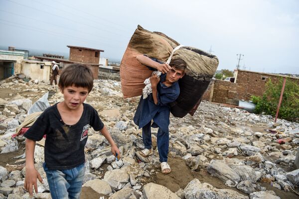 Молодые люди спасают остатки вещей из развалин домов после внезапного наводнения в Чарикаре, провинция Парван, Афганистан - Sputnik Тоҷикистон