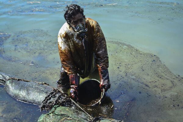 Мужчина очищает воду от разлившейся у берегов Маврикия нефти - Sputnik Тоҷикистон