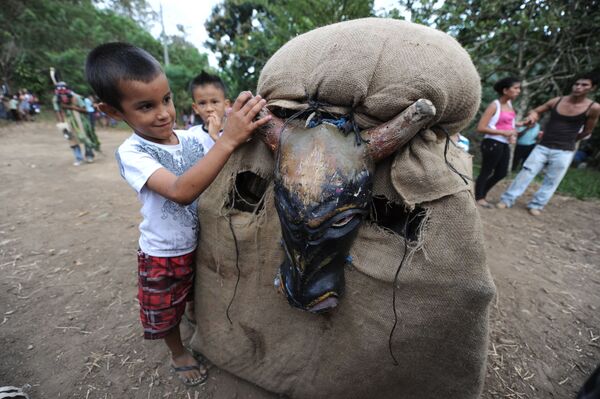 Мальчик играет с участником фестиваля Feast of the Devils в костюме быка в Коста-Рике  - Sputnik Таджикистан