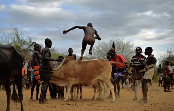 Мужчина во время церемонии прыжков через быка в Эфиопии  - Sputnik Таджикистан