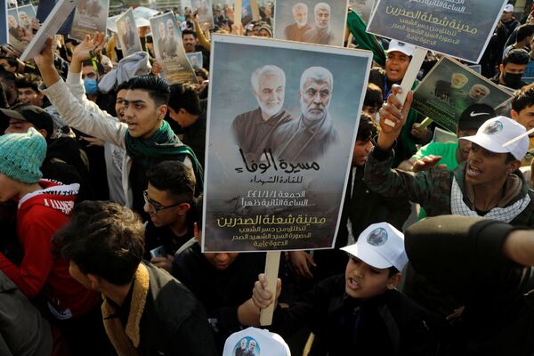 Люди с плакатами во время первой годовщины со дня смерти иранского командира Касема Сулеймани и иракского командира Абу Махди аль-Мухандиса в Багдаде - Sputnik Таджикистан