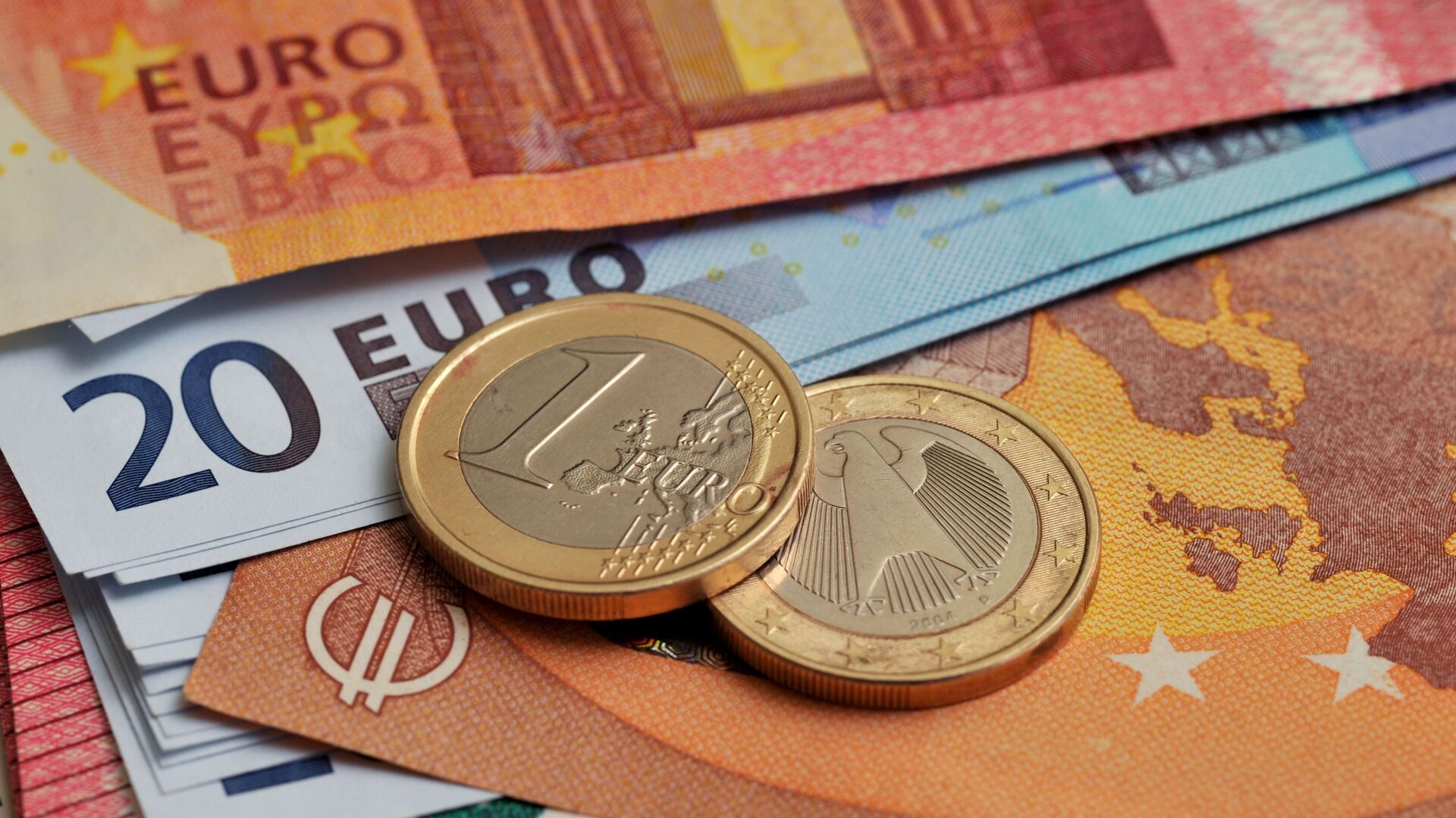 Монеты номиналом 1 евро на фоне банкнот номиналом 10 и 20 евро.  - Sputnik Таджикистан, 1920, 27.04.2021