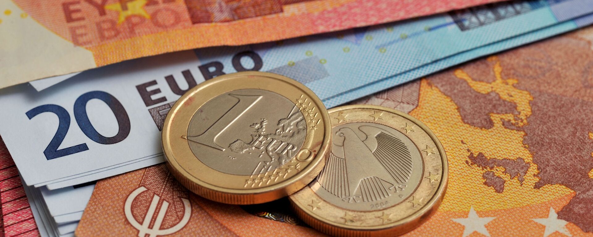 Монеты номиналом 1 евро на фоне банкнот номиналом 10 и 20 евро.  - Sputnik Таджикистан, 1920, 04.02.2021