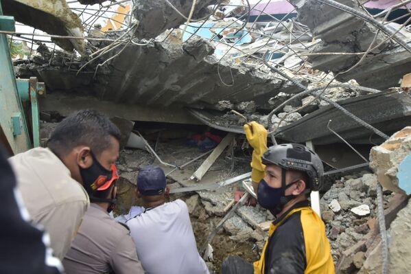 Спасатели ищут выживших в больнице, разрушенной землетрясением в городе Мамаджу, Индонезия - Sputnik Таджикистан