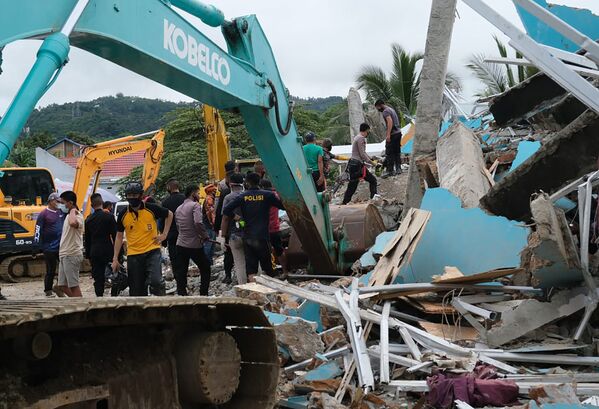 Спасатели ищут выживших среди руин здания, поврежденного в результате землетрясения в Мамуджу, Индонезия - Sputnik Таджикистан