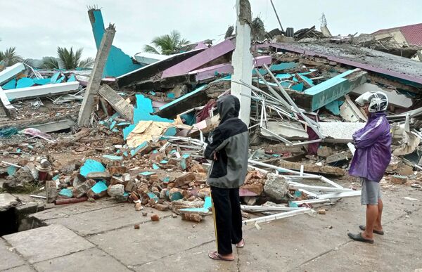 Люди смотрят на разрушенный землетрясением дом на Сулавеси, Индонезия - Sputnik Таджикистан