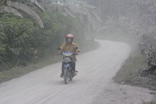 Мужчина во время проезда по покрытой пеплом улице после извержения вулкана Семеру в Индонезии  - Sputnik Таджикистан