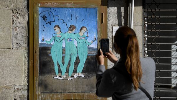 Женщина фотографирует на свой мобильный телефон новую работу итальянского уличного художника TvBoy под названием «Три вакцины» - Sputnik Таджикистан