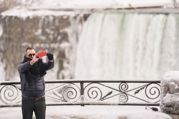Мужчина во время селфи напротив водопада Хорсшу-Фолс, входящего в Ниагарские водопады в Канаде  - Sputnik Тоҷикистон