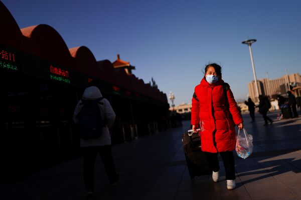 Путешественница в защтной маске у железнодорожного вокзала в Пекине, Китай - Sputnik Тоҷикистон
