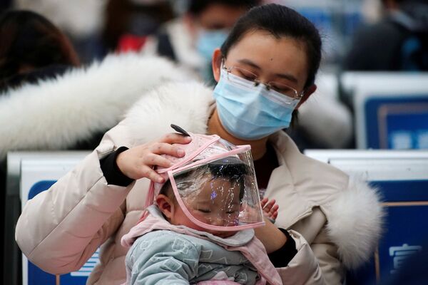 Женщина с ребенком в защитных масках на вокзале в Шанхае, Китай - Sputnik Тоҷикистон