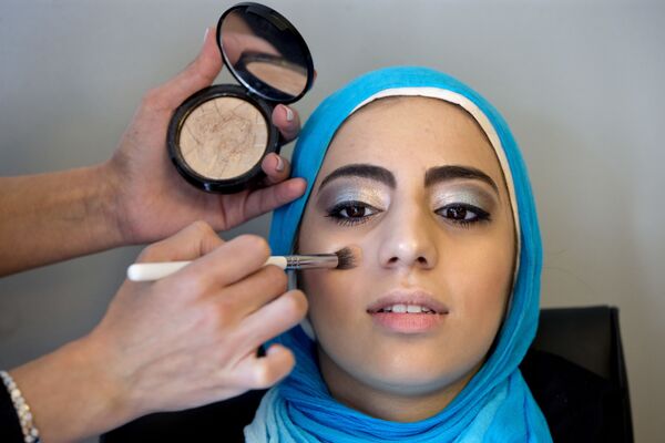 Молодая девушка в хиджабе делает макияж, готовясь к выпускному вечеру в старшей школе в Джермантуане, США - Sputnik Таджикистан